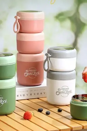 Assorted color double tier and tier insulated lunch box bow, on table with decorative background